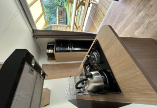 Cocina moderna en una cabaña de Camping Seasonova Les Marguerites, Francia, con vista a la terraza de madera.