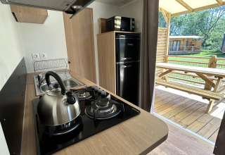 Cocina moderna en una cabaña de Camping Seasonova Les Marguerites, Francia, con vista a la terraza de madera.