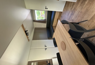 Interior de una cabaña moderna con mesa de comedor, sillas negras y sofá en Camping Seasonova Les Marguerites, Francia.