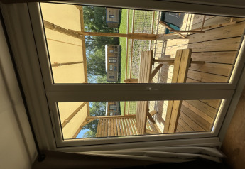 Foto taget gennem vindue fra en hytte hos Camping Seasonova Les Marguerites i Frankrig, udendørs træterrasse.