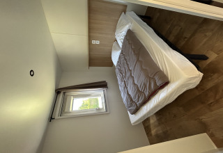 Dormitorio de una cabaña Cottage en Camping Seasonova Les Marguerites, Francia, con cama doble y ventana.