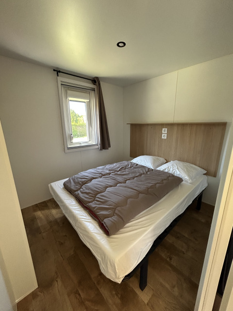 Dormitorio de una cabaña Cottage en Camping Seasonova Les Marguerites, Francia, con cama doble y ventana.