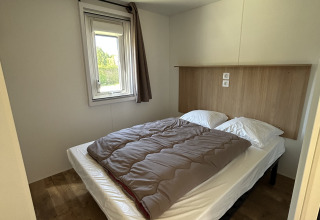 Dormitorio de una cabaña Cottage en Camping Seasonova Les Marguerites, Francia, con cama doble y ventana.