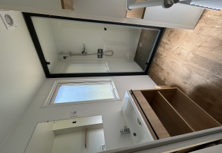 Baño moderno con ducha, piso imitación madera y lavabo en una cabaña de Camping Seasonova Les Marguerites, Francia.