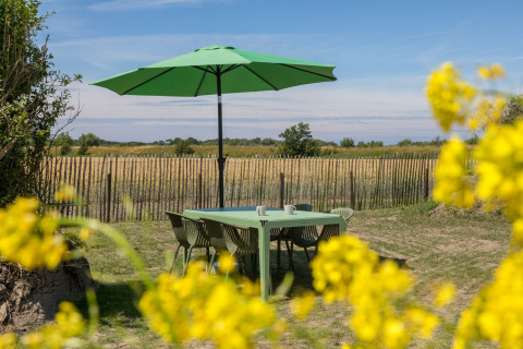 Buitenterras met groene tafel, stoelen en parasol in een landelijke omgeving bij Welcome In - Zeeland.