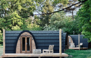 Hyggelige hytter med buet tag og træterrasse set ved Cabin at Thuysgrond i Holland om sommeren.