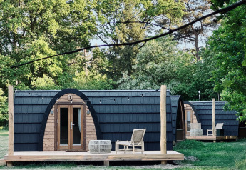 Hyggelige hytter med buet tag og træterrasse set ved Cabin at Thuysgrond i Holland om sommeren.