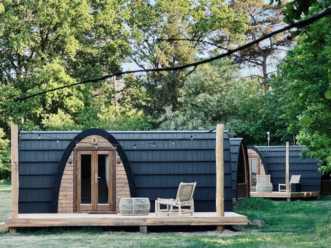 Hyggelige hytter med buet tag og træterrasse set ved Cabin at Thuysgrond i Holland om sommeren.