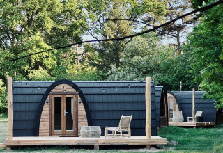 Hyggelige hytter med buet tag og træterrasse set ved Cabin at Thuysgrond i Holland om sommeren.