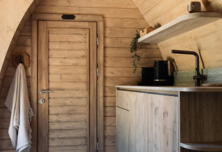 Holzverkleidetes Interieur mit Küchenzeile und Tür in der Cabin at Thuysgrond, Niederlande, stilvoll gestaltet.