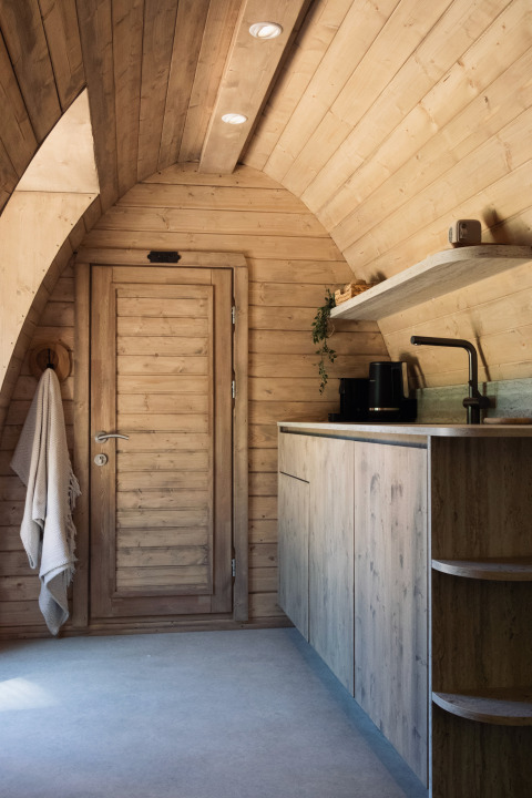 Træbeklædt interiør af en komfur og dør i Cabin at Thuysgrond, Holland, hyggeligt og moderne design.