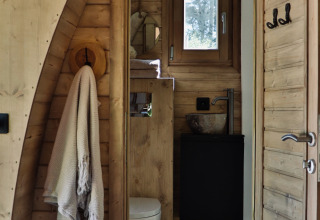 Badeværelse i en træhytte med håndklæde, toilet og lille vindue, set i Cabin at Thuysgrond, Holland.