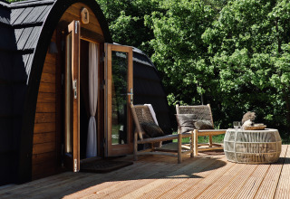 Buitenterras aan Cabin at Thuysgrond in Nederland met twee stoelen en een tafel, midden in het groen.