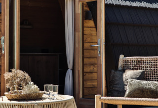 Outdoor seating area with wicker furniture in front of a wooden cabin at Cabin at Thuysgrond, Netherlands.