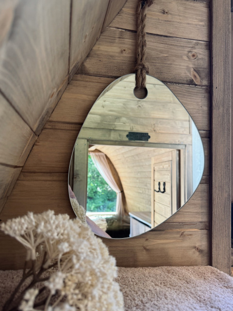 Reflejo en espejo de una cabaña de madera en Cabin at Thuysgrond, Países Bajos, con interior acogedor.