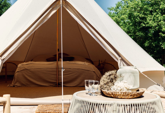 Tienda Bell glamping con cama cómoda, decoración rústica y entorno natural, ideal para escapadas únicas.