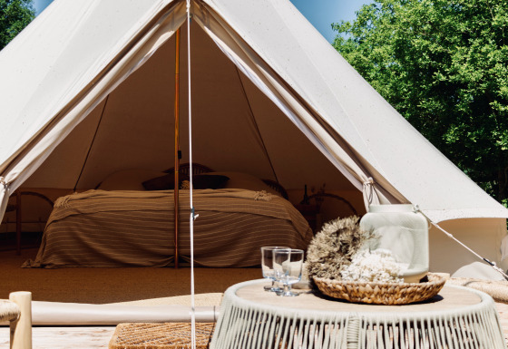 Gezellige Bell-tent met ruim bed en stijlvolle decoratie, ideaal voor een unieke glampingervaring in de natuur.