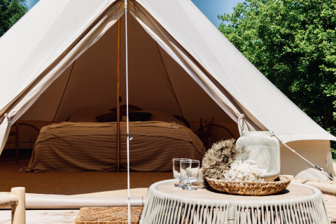 Luksuriøs Bell-tipi med komfortabel seng, rustik indretning og udsigt til natur, perfekt til glamping.