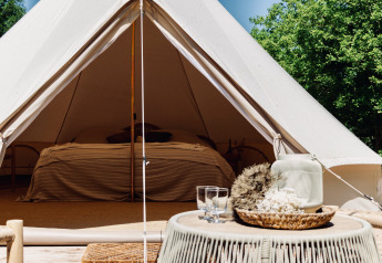 Sfeervolle Bell-tent met comfortabel bed en rustiek interieur, perfect voor een ontspannen glamping ervaring.