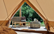 Vista dall'interno di una tenda tipi Bell a Thuysgrond, Paesi Bassi, con panca e tavolino all'aperto.