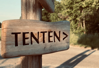 Wooden sign says 'TENTEN' with right arrow, photo at Bell tent, Thuysgrond, Netherlands, in natural setting.