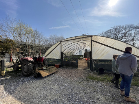 Mensen betreden een serre naast een tractor op vakantiepark Feather Down Foxglove Farm in Zuidoost-Engeland.