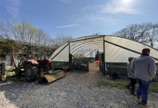 Mensen lopen een kas binnen naast een tractor op Feather Down Foxglove Farm vakantiepark in Zuidoost-Engeland.