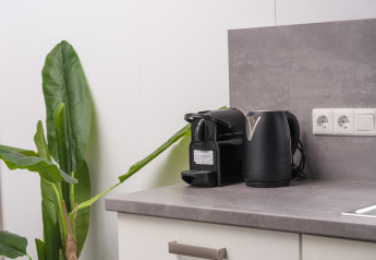 Moderne keukenblad met waterkoker, koffiezetapparaat, plant en stopcontacten in Holiday Park Mölke, Nederland.