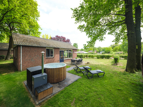 Buitenbeeld van het FC Mölke verblijf in Holiday Park Mölke, Nederland, met hottub, ligstoelen en zitplaats.