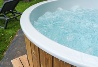 Outdoor-Whirlpool mit Holzverkleidung und Liegestuhl im Garten am FC Mölke Stadion in den Niederlanden.