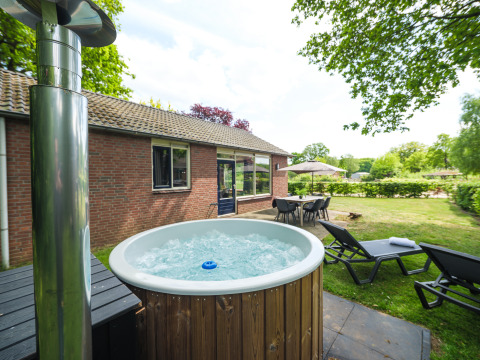Bubbelbad, ligstoelen en eettafel aan het FC Mölke stadium lodge in Holiday Park Mölke, Nederland.