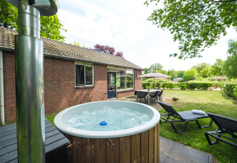 Bubbelbad, ligstoelen en eettafel aan het FC Mölke stadium lodge in Holiday Park Mölke, Nederland.