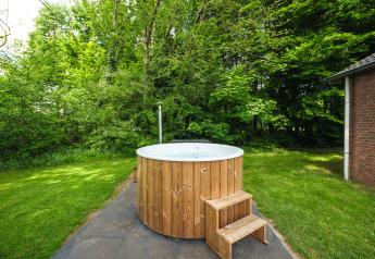 Outdoor wooden hot tub next to a lodge at FC Mölke stadium in Holiday Park Mölke, Netherlands, summer view.