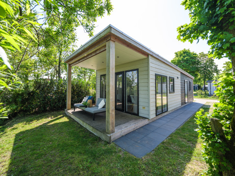 Buitenaanzicht van River lodge in Holiday Park Mölke in Nederland, met gezellig terras en groene tuin.
