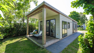 Außenansicht der River Lodge im Holiday Park Mölke in den Niederlanden, mit Terrasse und Garten.