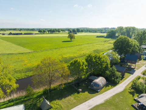 Vue aérienne d’une tiny house près d’une rivière et de champs verts au Holiday Park Mölke, Pays-Bas.