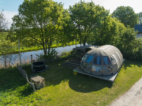Vista aérea de la tiny house Riverdome con baño y jacuzzi en Holiday Park Mölke, Países Bajos, junto a un río.