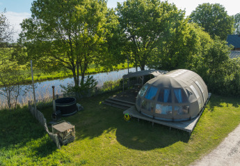 Luchtfoto van de Riverdome tiny house met badkamer en hottub bij Holiday Park Mölke, Nederland, aan het water.