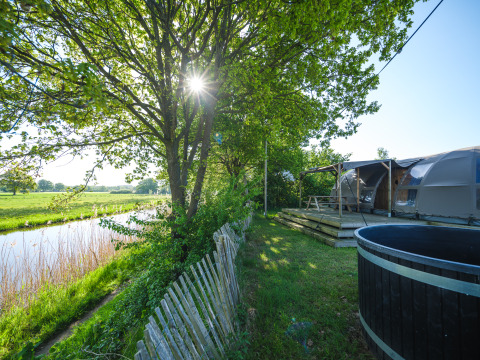 Vista soleada junto al río con Riverdome, terraza de madera, mesa de picnic y jacuzzi en Holiday Park Mölke.
