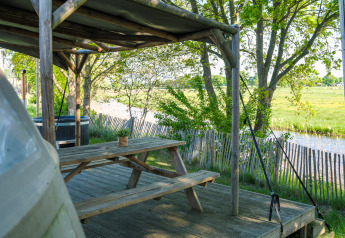 Coin extérieur avec banc en bois près de la rivière, Riverdome tiny house au Holiday Park Mölke, Pays-Bas.