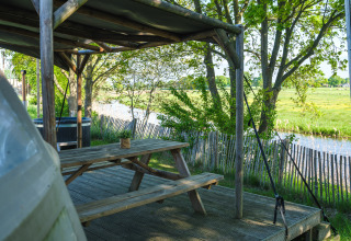 Udendørs siddeplads med træbord og overdækning ved en flod, Riverdome på Holiday Park Mölke, Holland.
