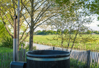 Vue sur les prairies vertes depuis un bain chaud extérieur au Riverdome, Holiday Park Mölke, Pays-Bas.