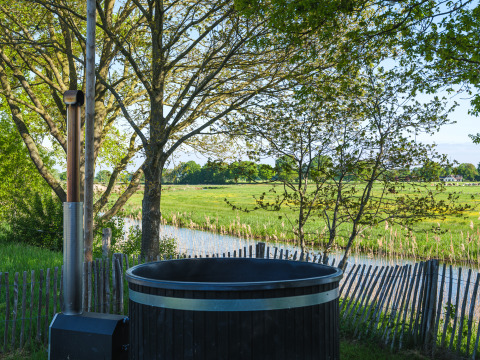 Vue sur les prairies vertes depuis un bain chaud extérieur au Riverdome, Holiday Park Mölke, Pays-Bas.
