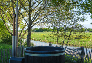 Blick auf grüne Wiesen und Fluss vom Außen-Whirlpool im Riverdome im Holiday Park Mölke, Niederlande.