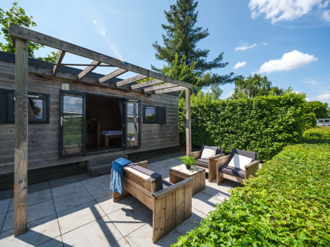 Gartenbereich eines Tiny House im Holiday Park Mölke, Niederlande, mit Holzterrasse und Loungemöbeln.
