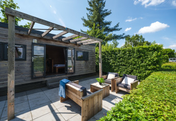 Buitenlounge van de Tiny House bij Holiday Park Mölke in Nederland, met houten meubilair en pergola.