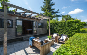 Buitenlounge van de Tiny House bij Holiday Park Mölke in Nederland, met houten meubilair en pergola.