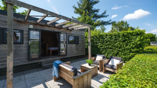 Espace détente extérieur du Tiny House au Holiday Park Mölke aux Pays-Bas, avec mobilier en bois et pergola.