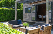 Buiten zithoek met houten meubels bij Tiny House in Holiday Park Mölke, omgeven door groen.