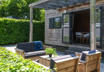 Buitenlounge met houten zetels aan Tiny House, Holiday Park Mölke, omringd door groen.
